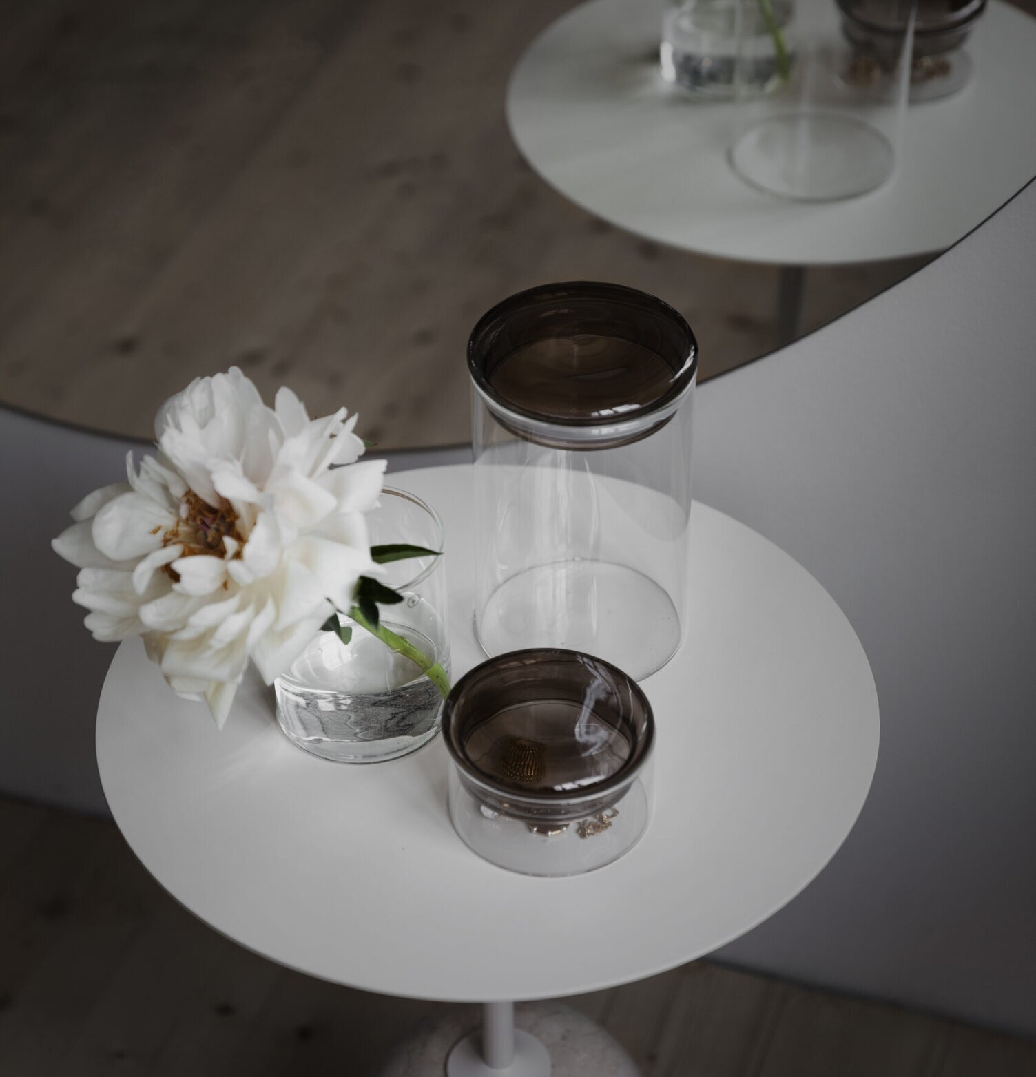 Bild av stilren scen med glasburkar och blomma